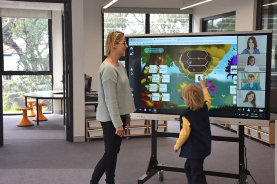 Student interacting with SMART board and collaborating with at-home students in real time